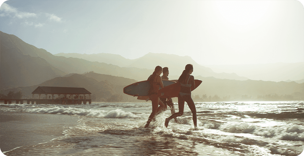 Three surfers going surfing at dusk